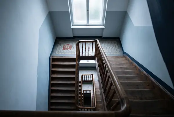 Looking down an old stairwell with worn timber treads and a turned wooden banister